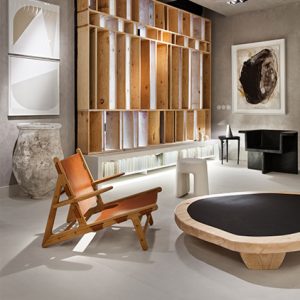 Detalle de la silla Hunting de Børge Mogensen en el espacio «Mixture Time» de Jaime Jurado para Casa Decor 2021, con estructura de madera, asiento de cuero y estantería de madera al fondo.