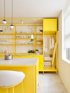 Detalle de la cocina amarilla Kitchen for Life con isla, baldas abiertas y mobiliario elevado