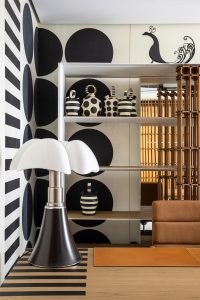 Detalle de la lámpara Pipistrello de Gae Aulenti, con pantalla blanca de cuatro lóbulos, base cónica negra y pie telescópico metálico, en el espacio JMM – José Martínez Medina de Casa Decor 2023, con decoración geométrica en blanco y negro.