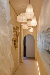 Pasillo decorado con lámparas colgantes de papel y mural artístico, diseño de ETC Arte e Interiorismo en Casa Decor 2024