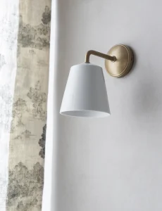 Aplique de pared Richmond de Corston, con pantalla de porcelana blanca y acabado en latón antiguo, instalado en el espacio de Salamandra Interiorismo.