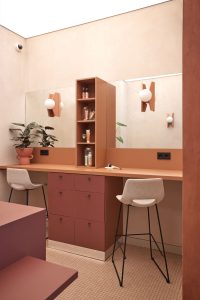 Tocador de cosmética ecológica con mueble central abierto y sillas de diseño, en boutique diseñada por Estudio Alegría