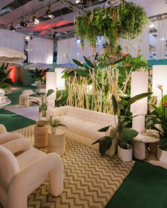 Detalle del área social del Kissing Room en MBFWMadrid, interiorismo con alfombras geométricas, mesas de piedra y un dosel verde suspendido.