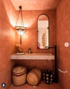 Baño del Espacio Nais diseñado por Studio Mo en Casa Decor 2023, ambiente cálido con paredes terracota y detalles artesanales.