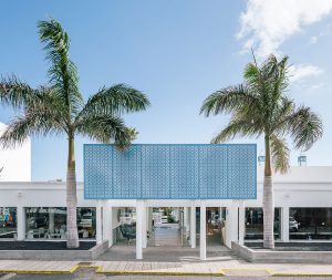 Reforma del complejo hotelero Oasis Lanz Beach Mate por Zooco Estudio en Lanzarote, fachada blanca con celosía azul y palmeras