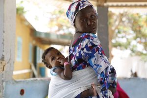 Mujer con su hijo en brazos en Senegal, beneficiaria de los programas sociales y sanitarios de Kassumay orientados a mujeres y niños.