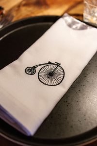 Servilleta con el logotipo de Triciclo en una mesa del restaurante, símbolo de la identidad gastronómica de Triciclo Catering en Casa Decor 2026
