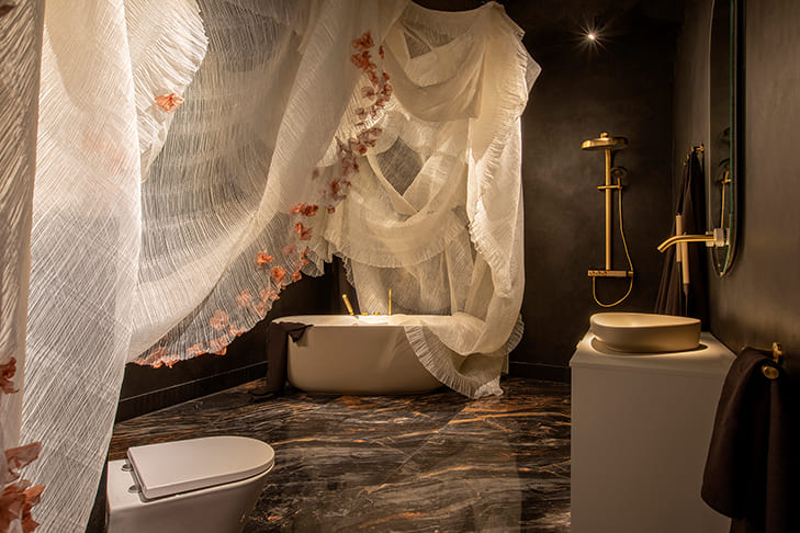 Baño elegante con bañera exenta Jacob Delafon y cortinas textiles escultóricas, diseño de U Interior Design con iluminación cálida