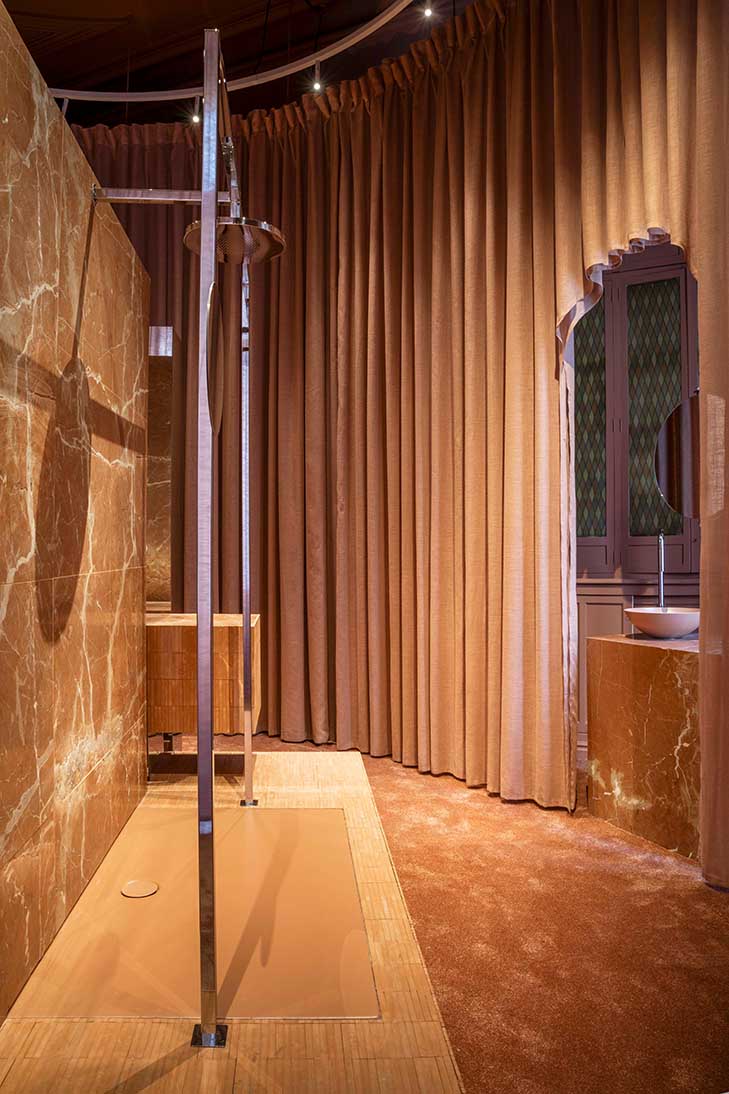 Zona de ducha del baño Fuerza Suave con cortinas terracota, mármol Rojo Levante y revestimientos cálidos