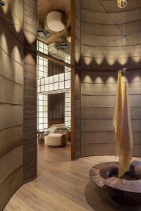 Antesala de The Listening Bar con revestimientos acústicos textiles de AITEX, madera de nogal Schotten & Hansen, escultura textil y luz cálida envolvente.