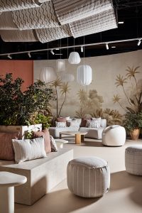 Zona de estar del espacio KASBAH en Casa Decor con mural Guinea de CR Class, sofás de líneas suaves, pufs arena y lámparas colgantes