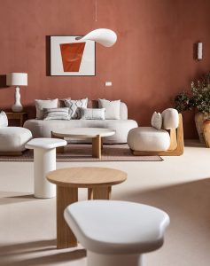 Rincón de tertulia con paredes terracota de Ecoclay, mobiliario blanco y mesas de madera en el espacio KASBAH de Casa Decor