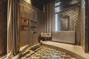 Baño Introspectio Suite de Nais con azulejos cerámicos de pequeño formato, paredes en tonos neutros, cortinas textiles y luz cálida, diseño de Estudio Querencia