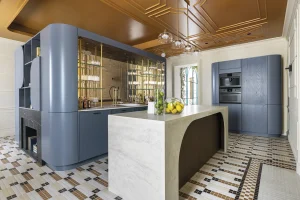 Cocina abierta con pavimento continuo de mosaico reciclado Hisbalit en tonos neutros, isla central y mobiliario integrado, diseño de Lemon Studio