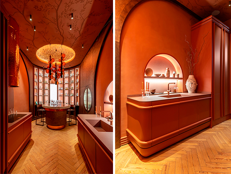 Cocina “Savia” de SixtyPro en Casa Decor 2026 con diseño envolvente en tonos terracota, iluminación cálida, mobiliario curvo y zona de bar integrada con estanterías retroiluminadas.