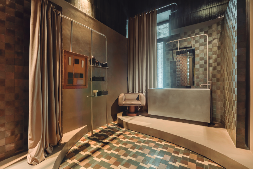 Antesala con ducha curva y cortinas de terciopelo, proyecto Nais de Estudio Querencia en Casa Decor 2026 con cerámica 10x10, microcemento y acero inoxidable