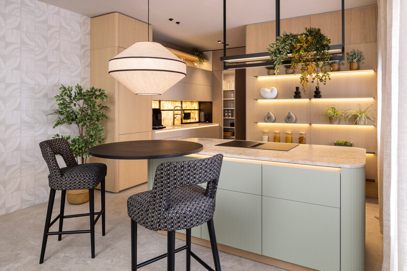 Cocina Leicht en Casa Decor 2026 con diseño orgánico, tonos claros, isla con almacenaje, iluminación integrada y zona office con mesa alta y estanterías decorativas.