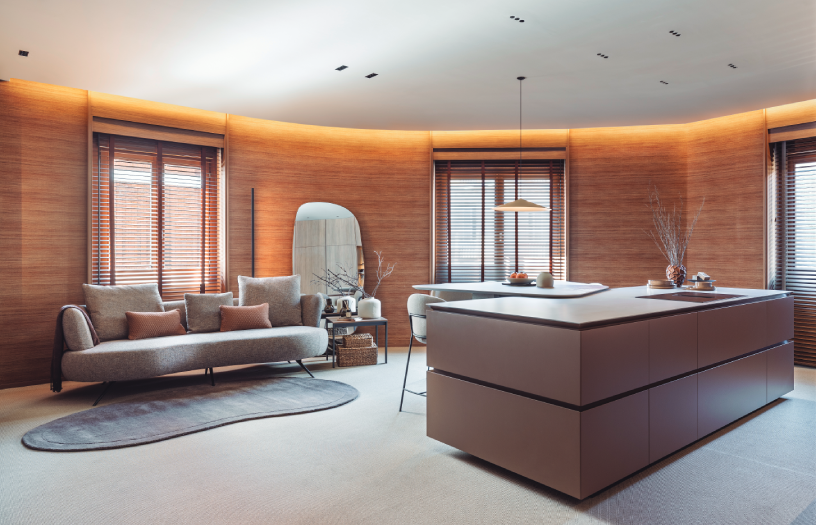 Cocina abierta con isla central y sofá Cocoon de líneas curvas en proyecto de interiorismo contemporáneo de Dica en Casa Decor 2026