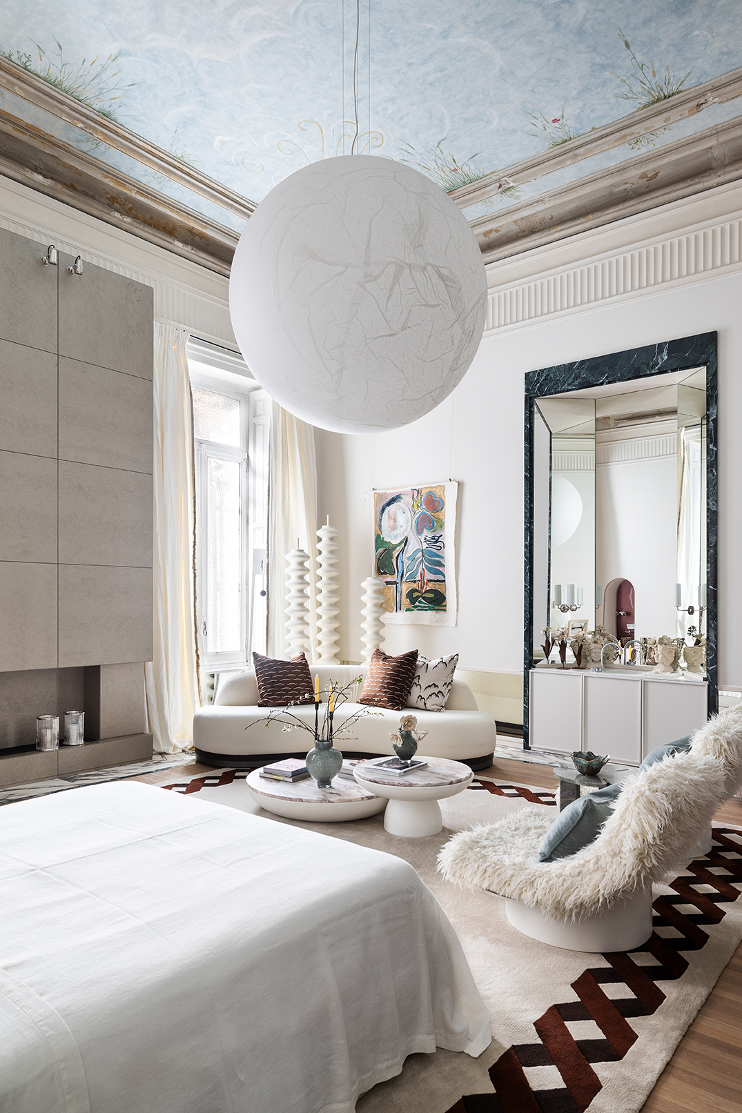 Interiorismo italiano en suite Casa Decor con gran lámpara esférica tipo luna, sofá curvo IVG Collection y radiadores de diseño Tubes