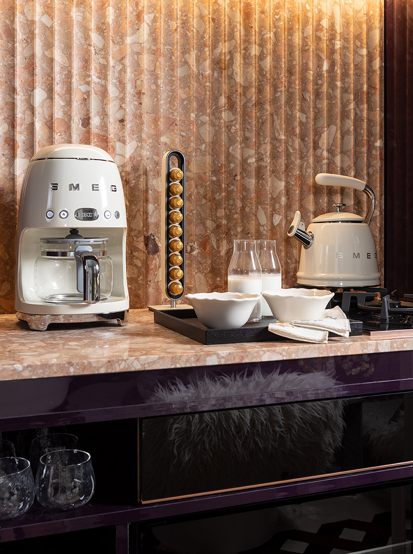 Electrodomésticos Smeg en desayunador de diseño con encimera de granito rosado Santamargherita y cápsulas de café en suite italiana