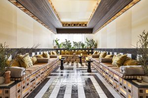 Salón simétrico con bancos corridos y pavimento cerámico geométrico en blanco y negro con piezas Imagine de Durstone, diseño de Impar Design en Casa Decor 2026