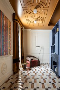 Salón de loft en Casa Decor 2026 con sillón de diseño, cortinas de terciopelo y suelo de mosaico