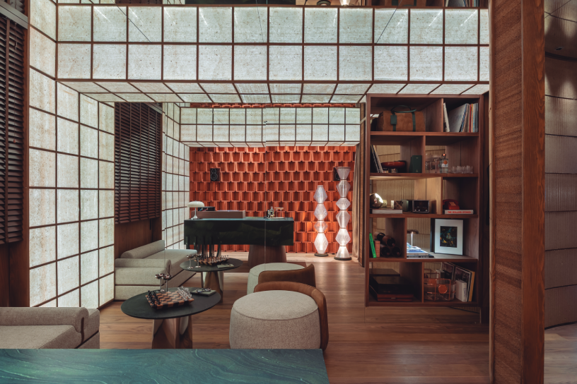 Interiorismo en Casa Decor 2026 con celosía roja y mobiliario en madera, espacio de ocio y relax inspirado en antiguos secaderos de tabaco