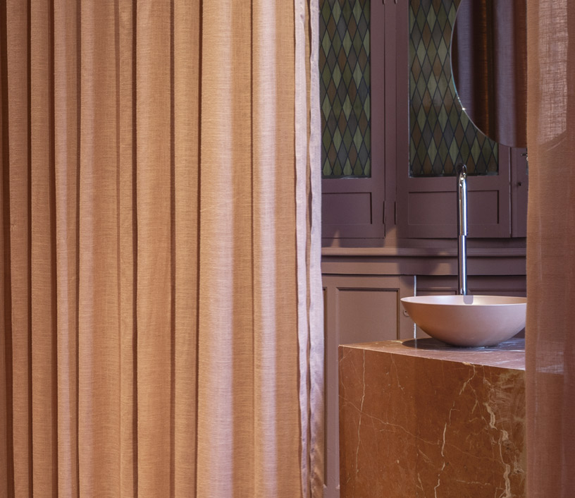Lavabo sobre encimera Avellino de Kaldewei junto a cortinas terracota y mármol rojo en Casa Decor 2026