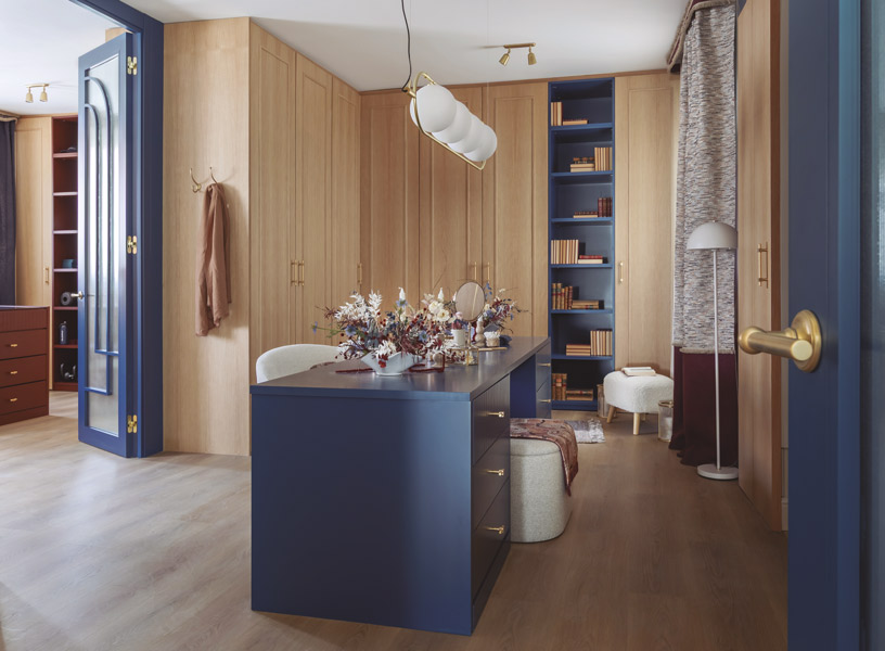 Vestidor del Espacio Sanrafael de Ana Guillem en Casa Decor 2026 con armarios de madera natural, isla central azul y pomos y tiradores en acabado latón de SC Handles & Lighting.