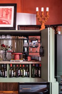 Detalle del mueble bar de Dos Latitudes con copas, botellas y piezas decorativas en la suite de TARQ Studio
