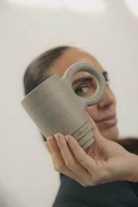 Taza Mar de cerámica sostenida frente al rostro de una mujer