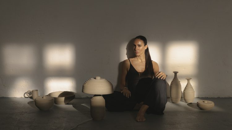 Diseñadora sentada entre jarrones, bowls y lámparas de cerámica de la colección Lempicka