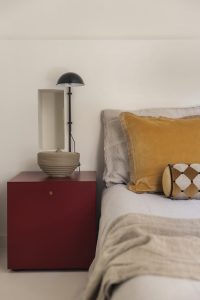 Pieza de cerámica de la colección Lempicka sobre una mesita roja junto a la cama
