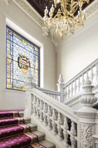 Vidriera policromada con escudo familiar en la escalera del Palacio de la Trinidad