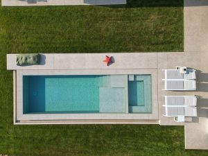 Piscina exterior con pavimento porcelánico Exagres y diseño rectangular sobre jardín