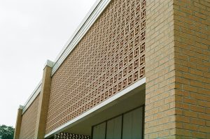 Fachada contemporánea protegida por una gran celosía modular de piezas cuadradas