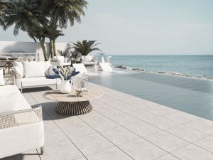 Terraza con piscina infinity y pavimento porcelánico Greco Gres frente al mar