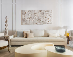 Salón diseñado por Beatriz Silveira para ITA – Italian Trade Agency en Casa Decor 2023, con sofá blanco, mesa de centro de formas curvas y lámpara Pipistrello de Gae Aulenti sobre una mesa auxiliar.